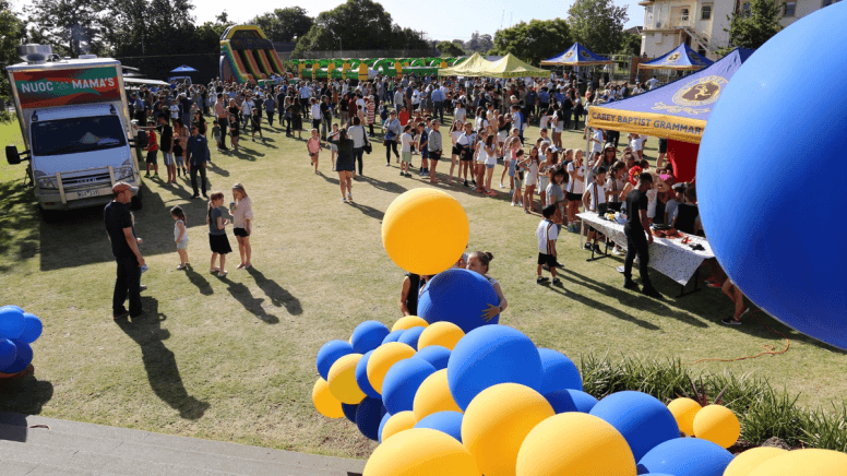 Carey school fair with lots of yellow and blue balloons on a field with markets and food trucks