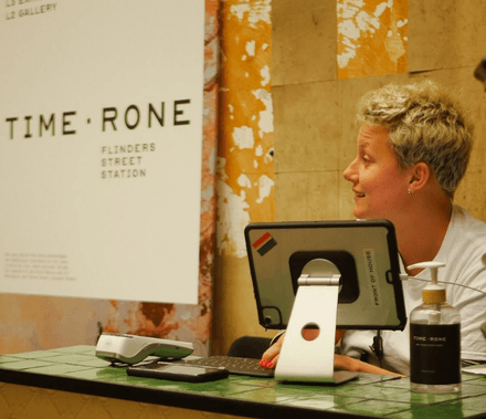 A staff member at the check-in desk for Time - Rone exhibition